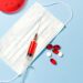 Mask and syringe lying on blue background